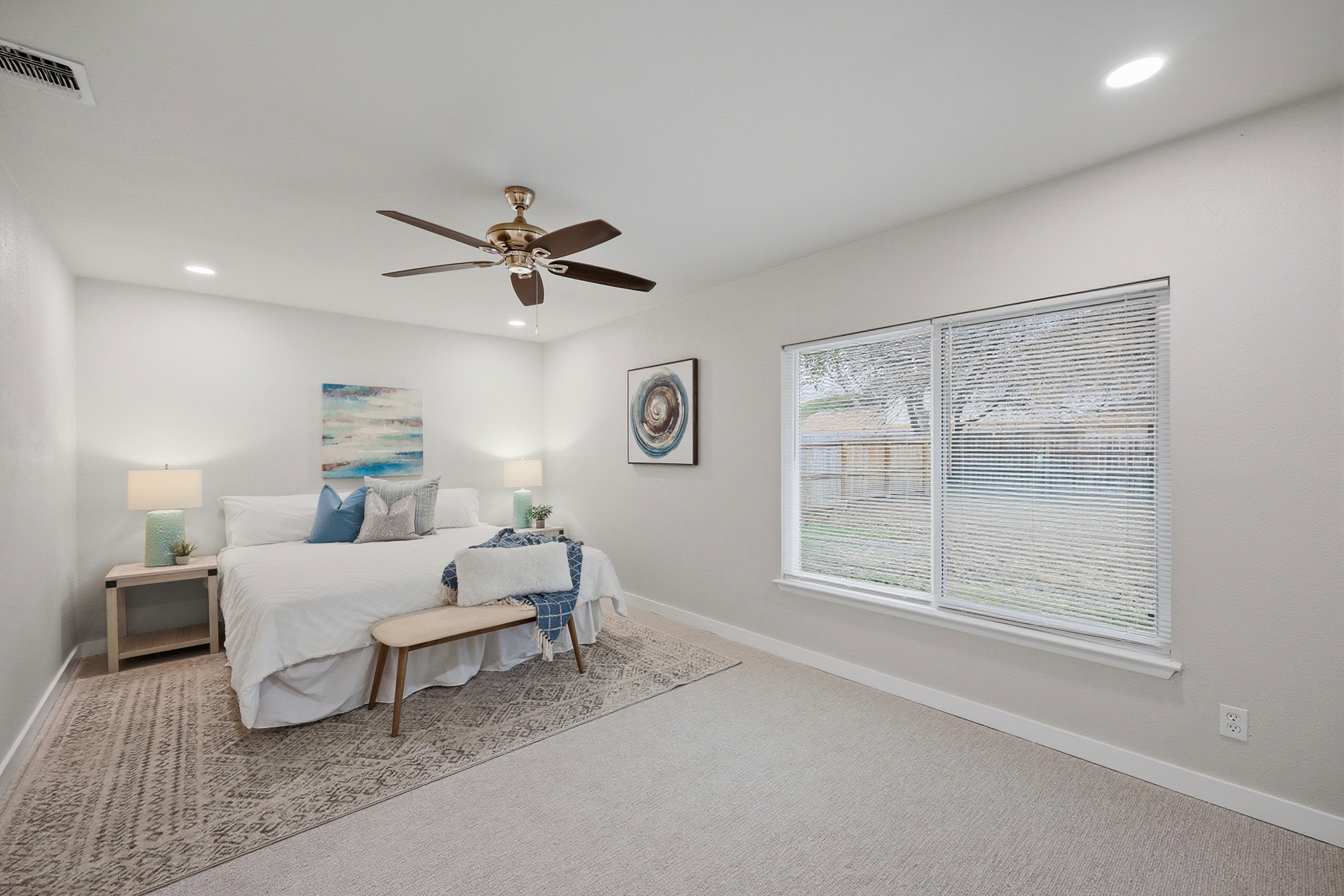 Primary bedroom with king bed, ceiling fan, large window, and en-suite access